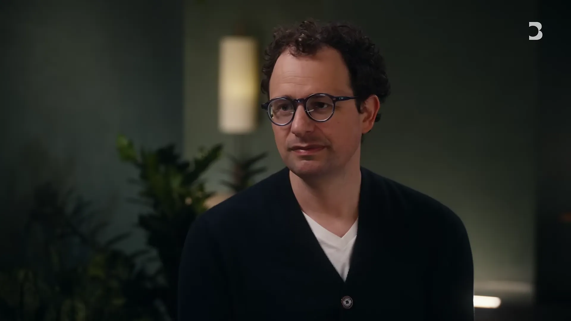 Dario Amodei in a green-lit room during the Bloomberg interview, discussing Anthropic's compute crunch and reliability